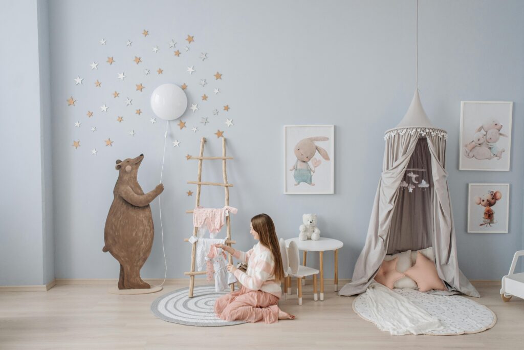 Woman arranging baby clothes in a beautifully decorated nursery with playful decor.